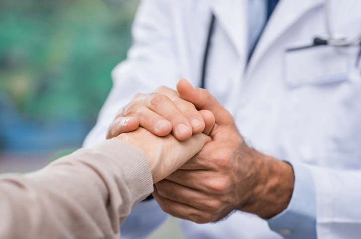 Médico acompañando con sus manos a un paciente durante una consulta